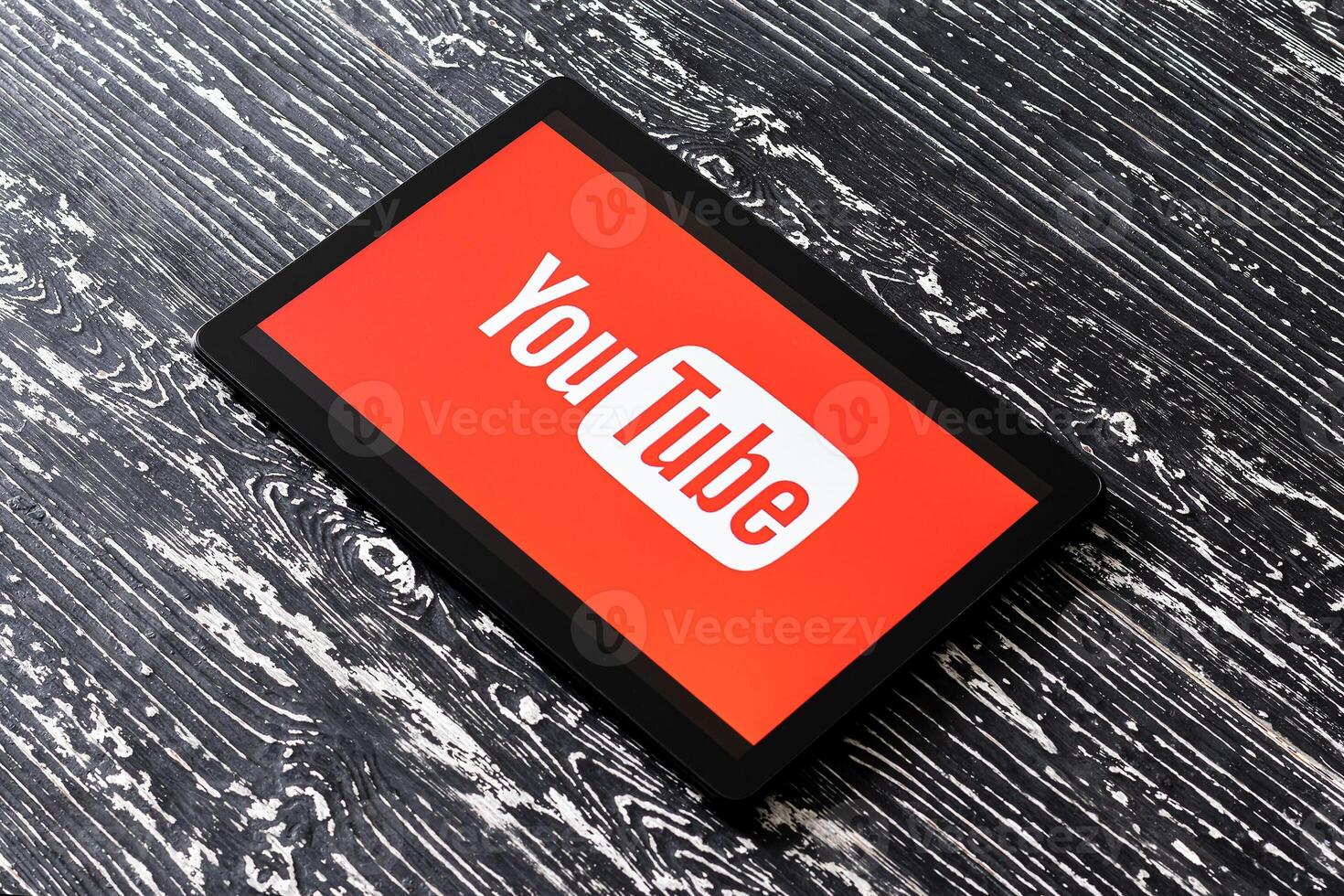 Tablet computer on a black wooden table with a social network YouTube logo on the screen. photo