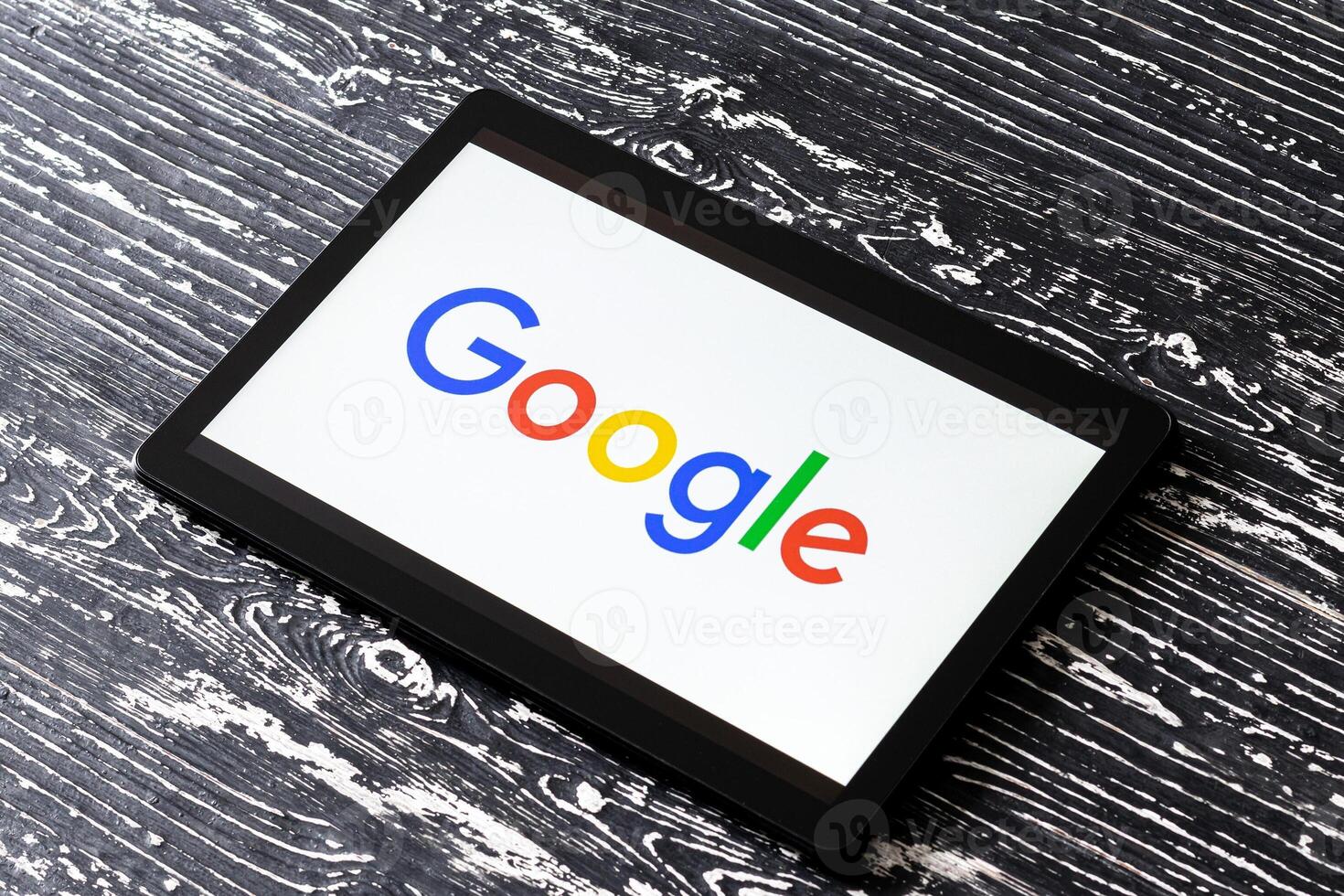 Tablet computer on a black wooden table with a search system google logo on the screen. photo