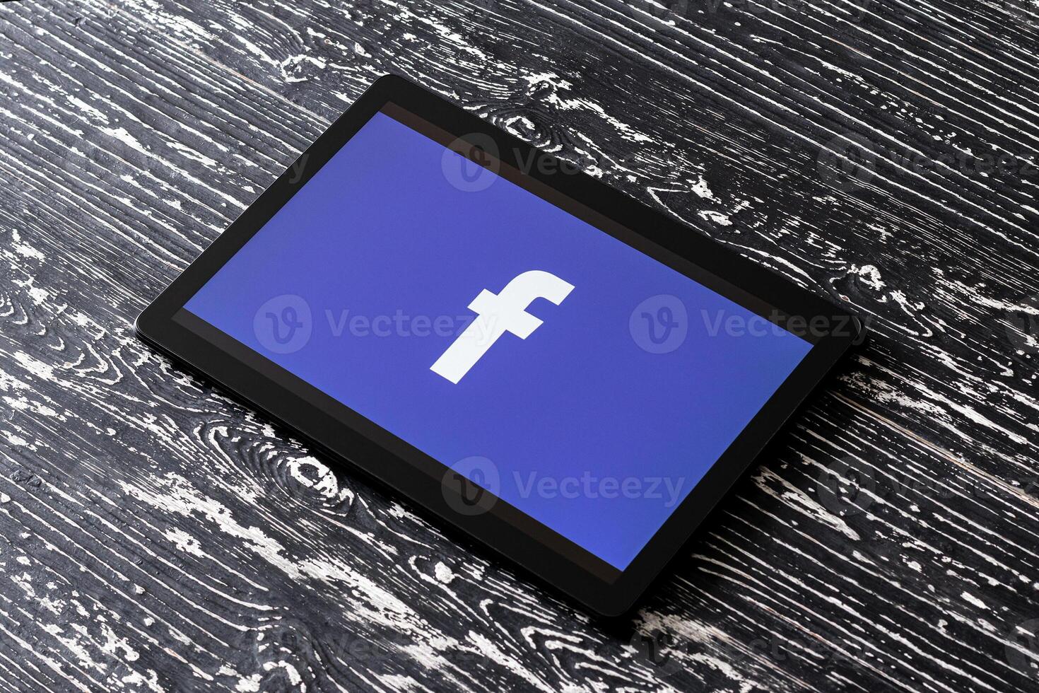 Tablet computer on a black wooden table with a social network facebook logo. photo