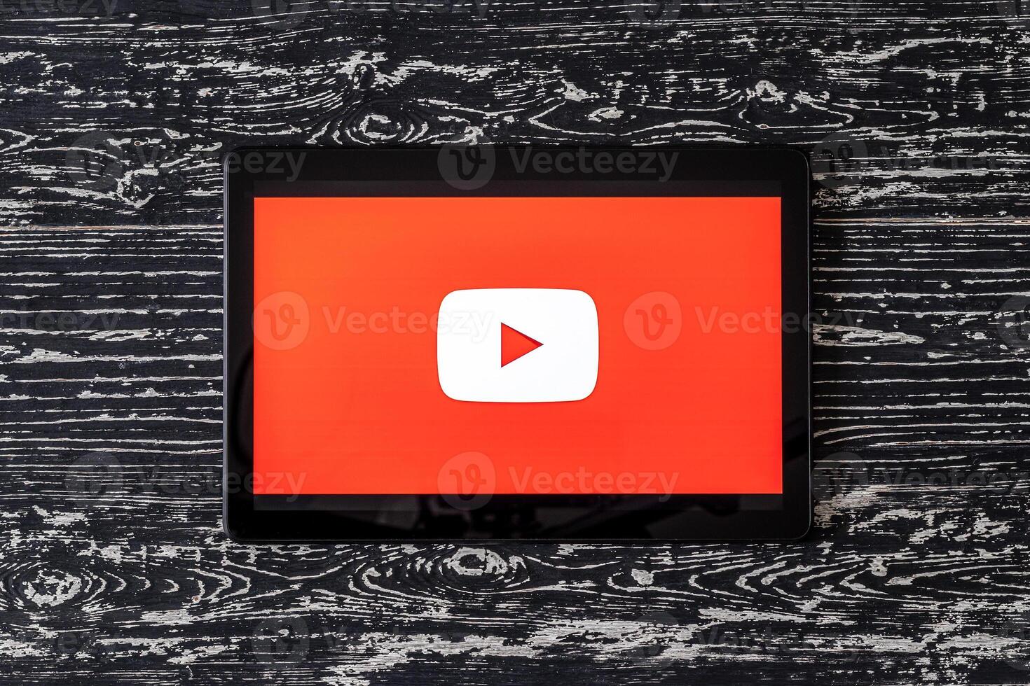Tablet computer on a black wooden table with a social network YouTube logo on the screen. photo