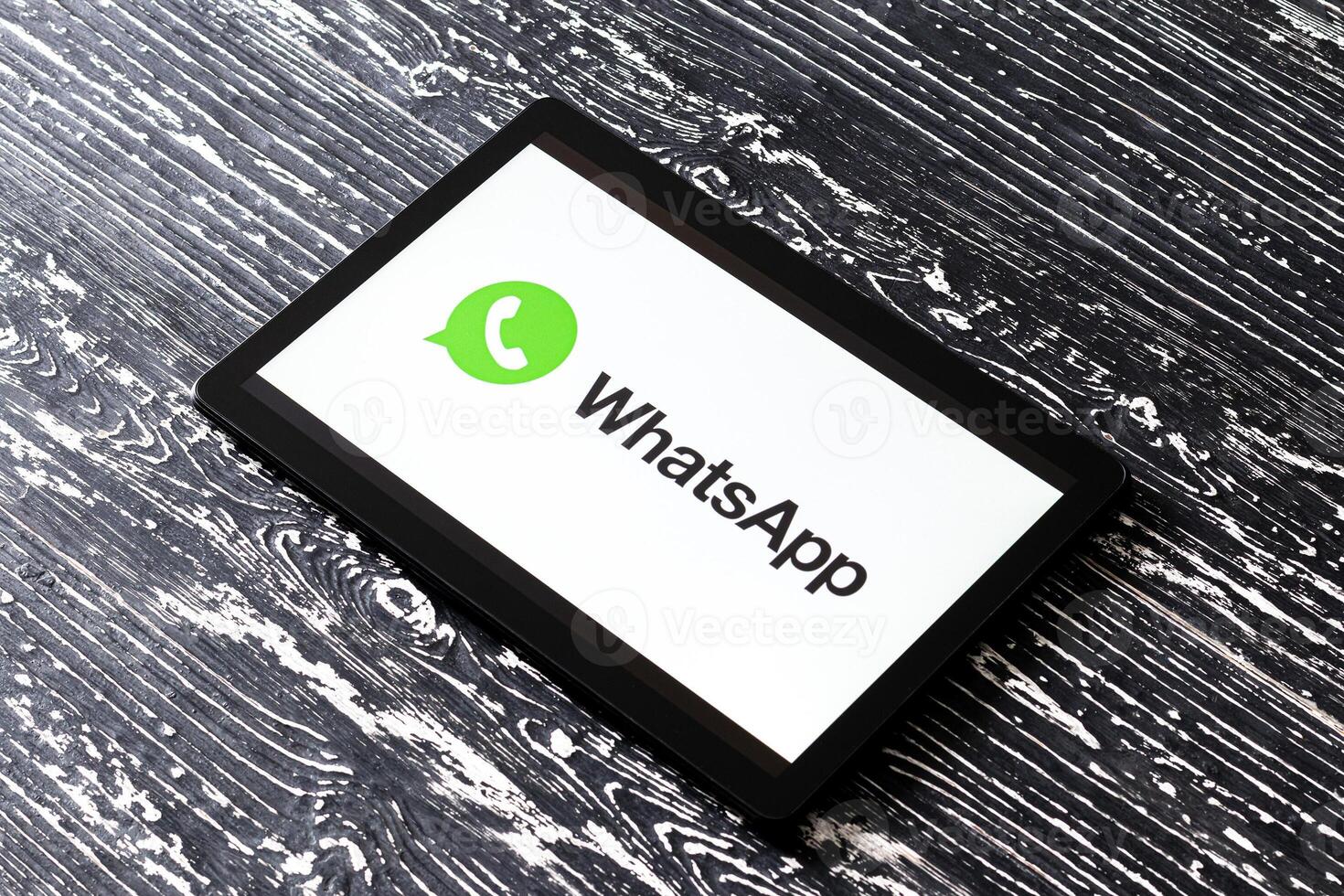 Tablet computer on a black wooden table with a messenger WhatsApp logo on the screen. photo
