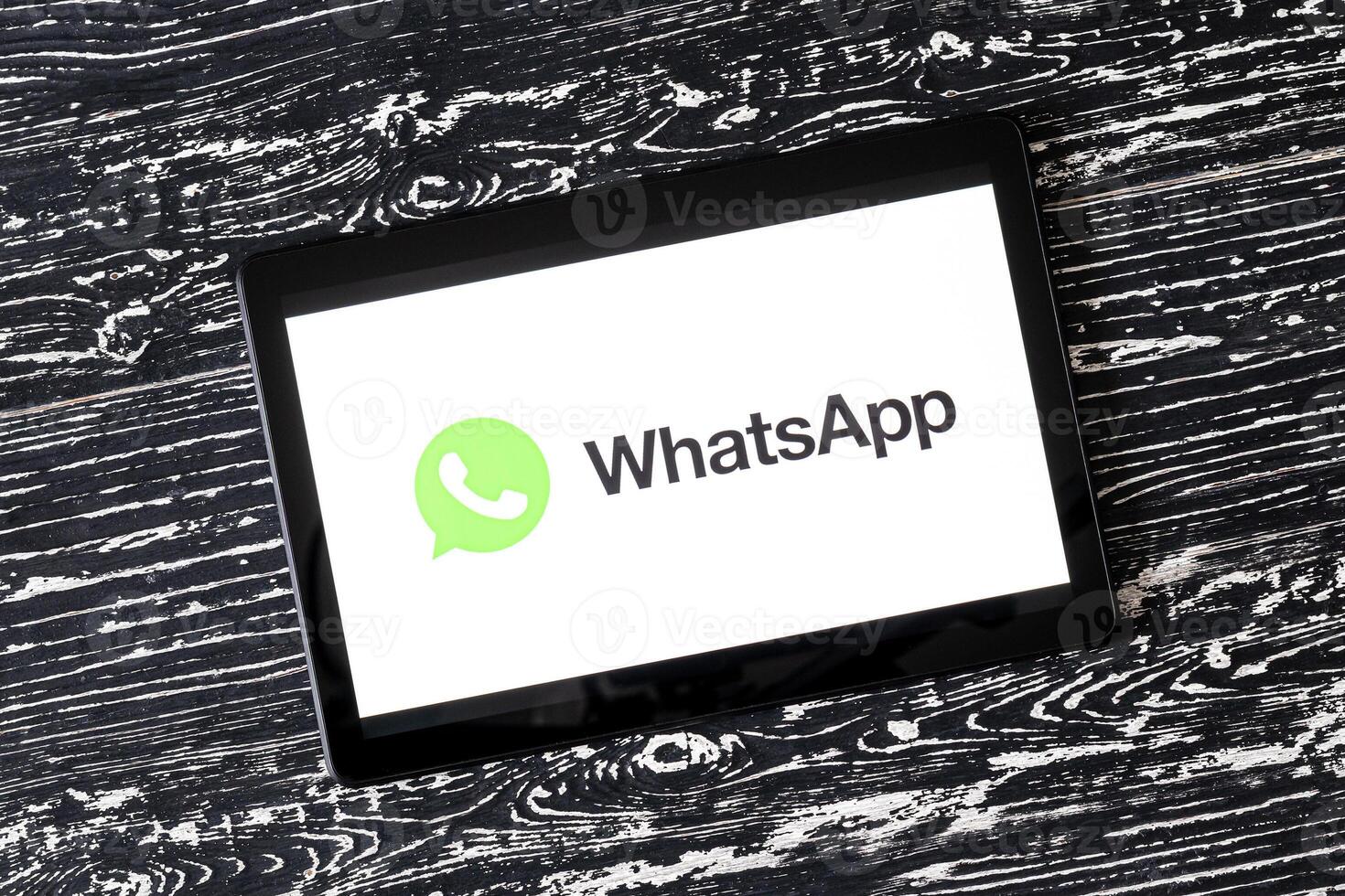 Tablet computer on a black wooden table with a messenger WhatsApp logo on the screen. photo