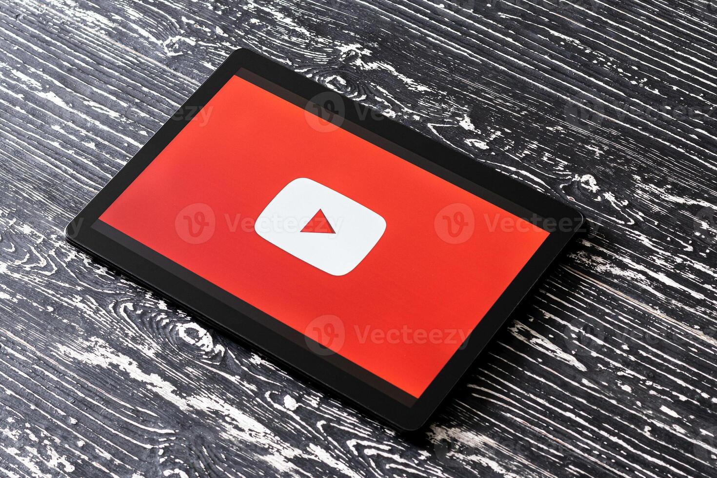 Tablet computer on a black wooden table with a social network YouTube logo on the screen. photo