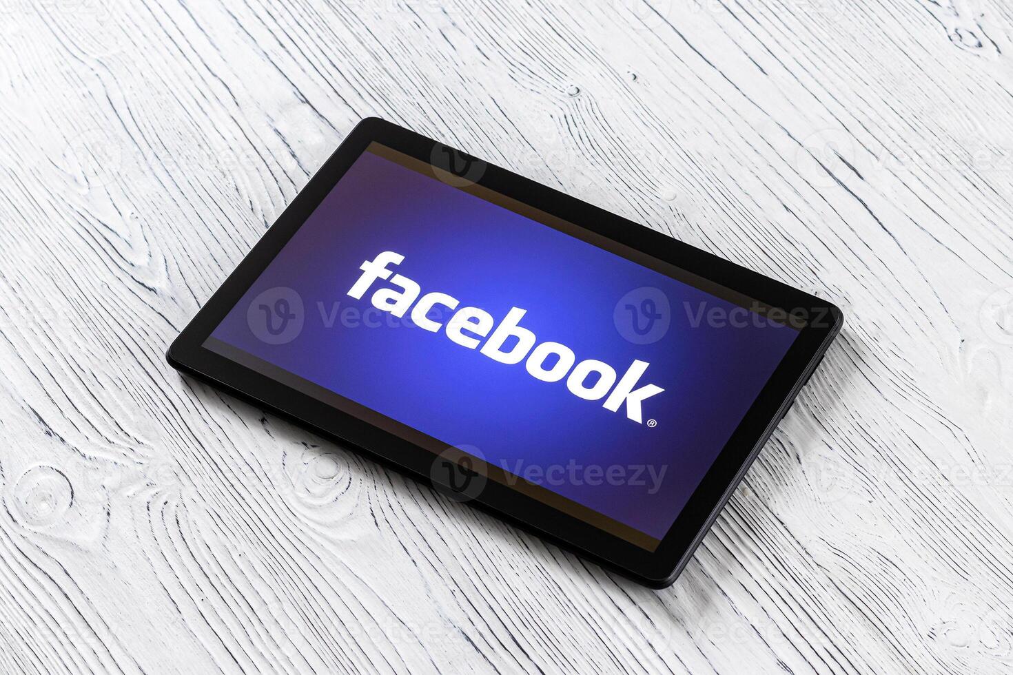 negro tableta computadora en un blanco de madera mesa con un social red Facebook logo en el pantalla. foto