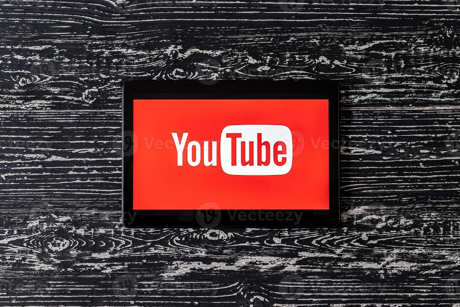 Tablet computer on a black wooden table with a social network YouTube logo on the screen. photo