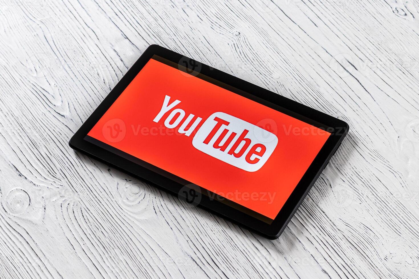 Black tablet computer on a white wooden table with a social network YouTube logo on the screen. photo