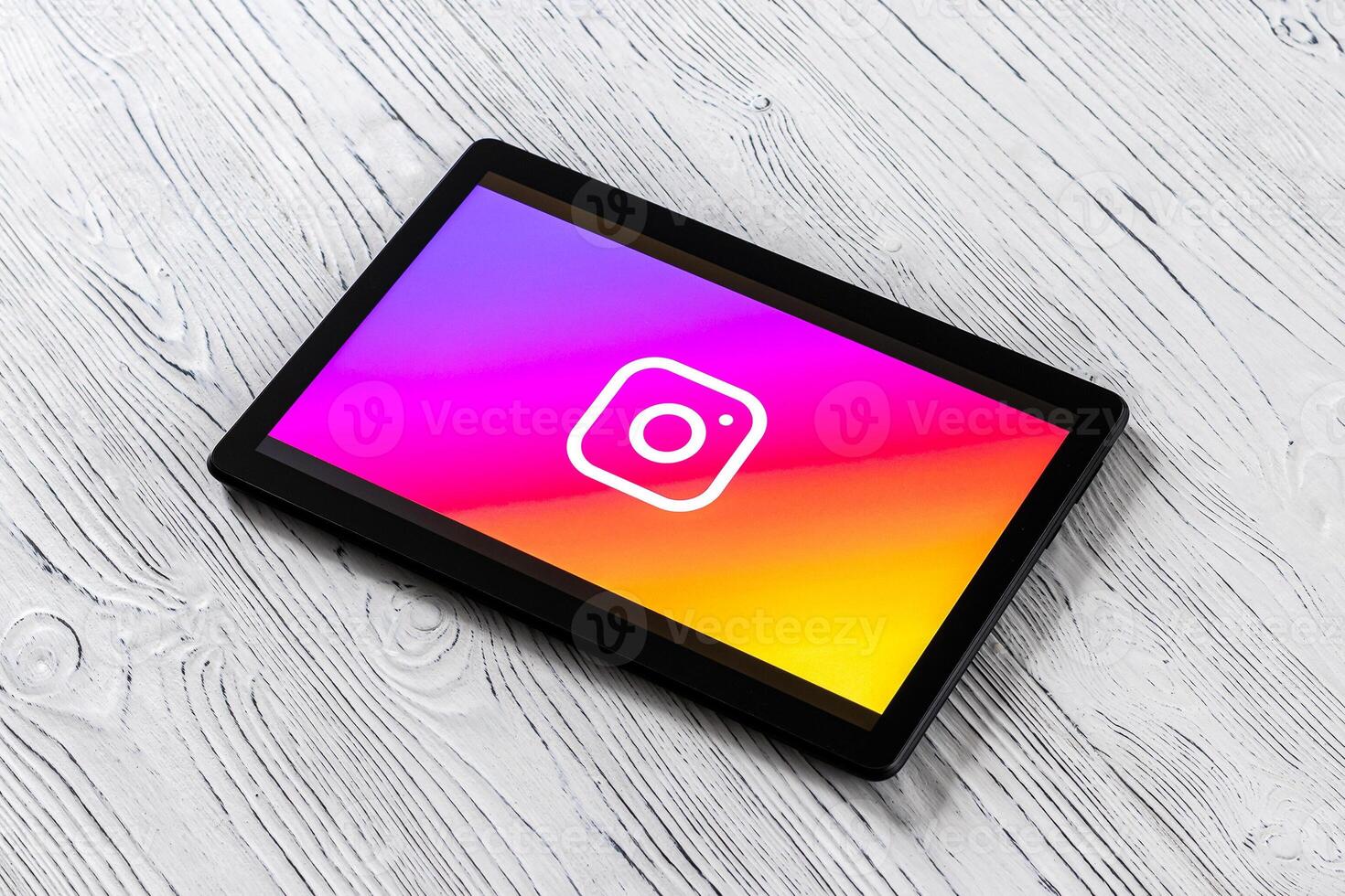 Black tablet computer on a white wooden table with a social network instagram logo on the screen. photo