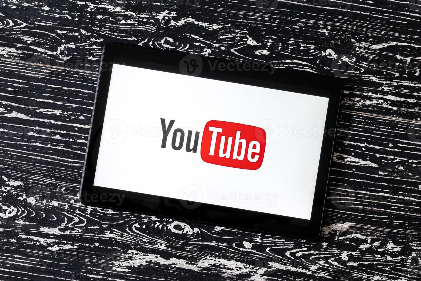 Tablet computer on a black wooden table with a social network YouTube logo on the screen. photo