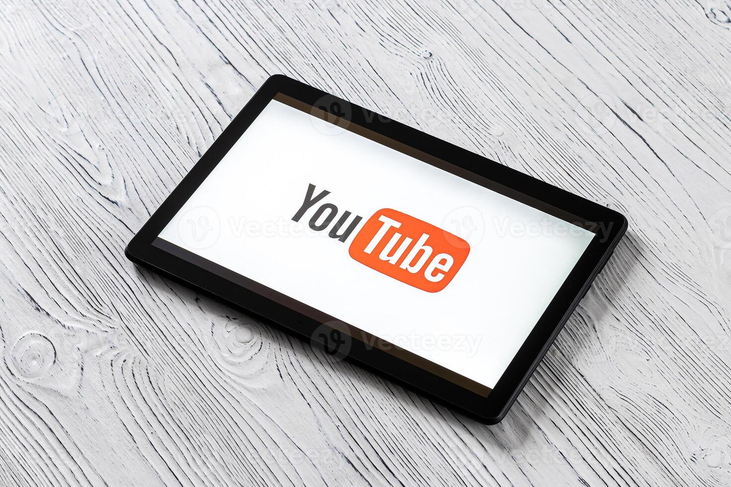 Black tablet computer on a white wooden table with a social network YouTube logo on the screen. photo