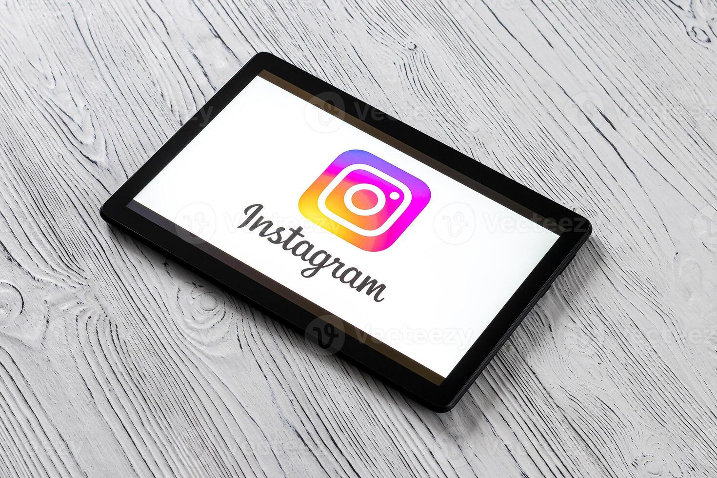 Black tablet computer on a white wooden table with a social network instagram logo on the screen. photo