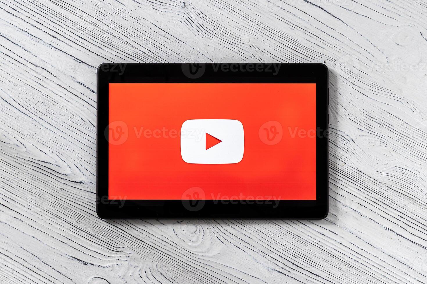 Black tablet computer on a white wooden table with a social network YouTube logo on the screen. photo