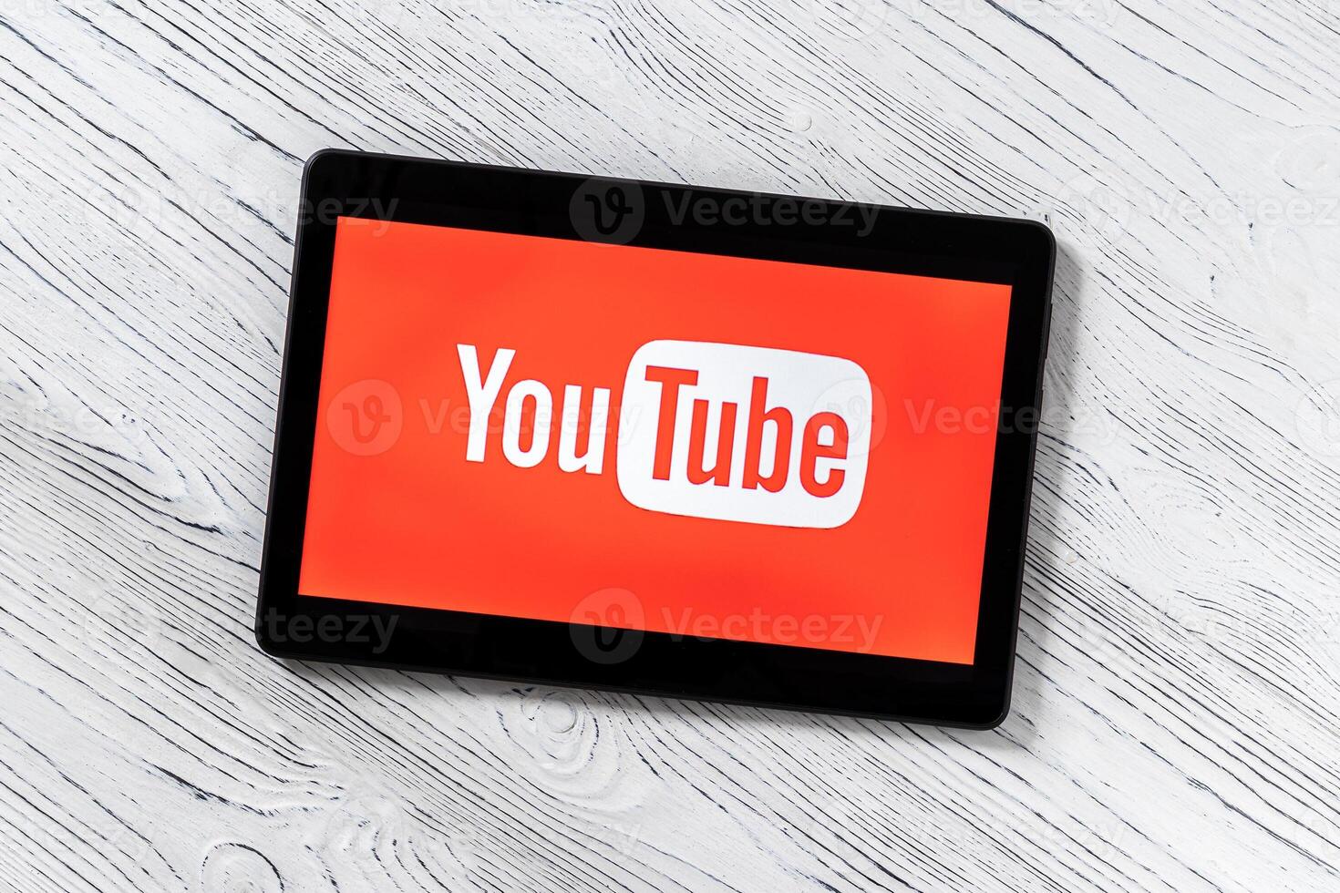 Black tablet computer on a white wooden table with a social network YouTube logo on the screen. photo