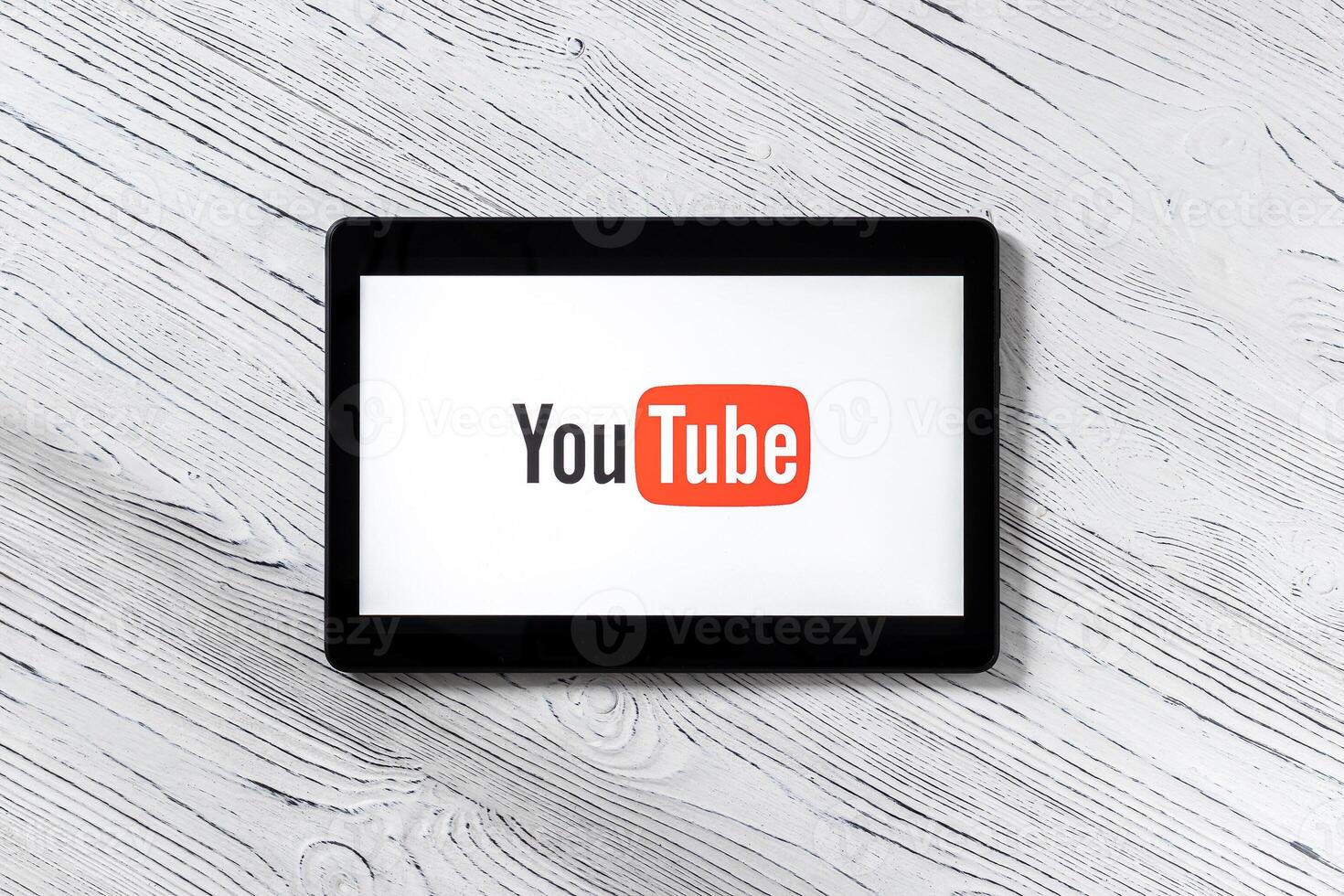 Black tablet computer on a white wooden table with a social network YouTube logo on the screen. photo