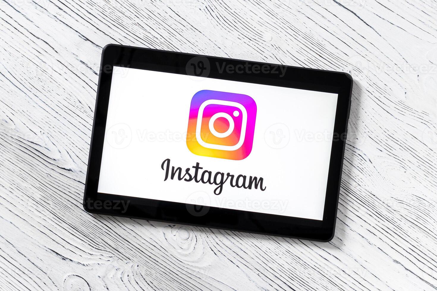 Black tablet computer on a white wooden table with a social network instagram logo on the screen. photo