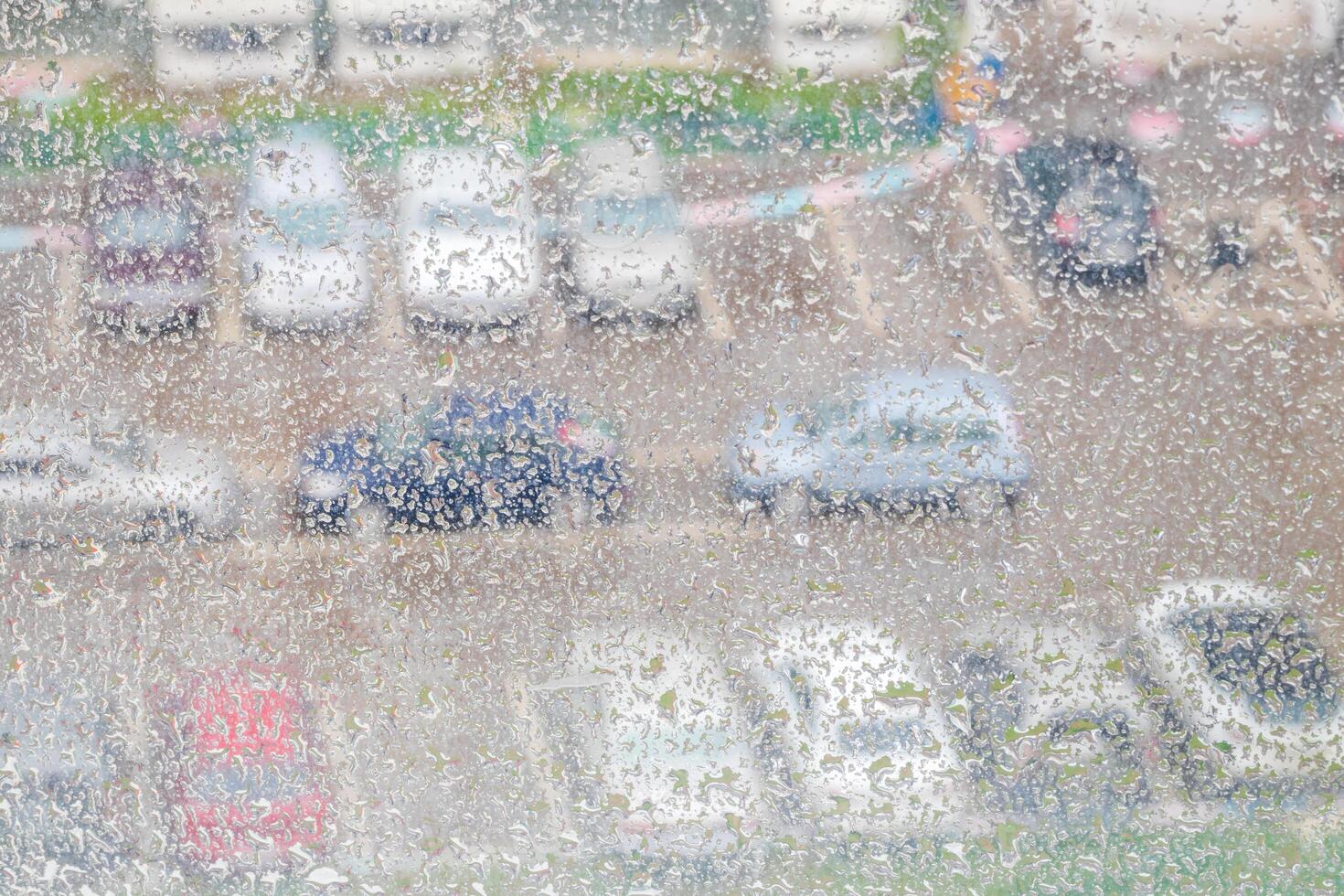 View through a rainy window on a blurred house and car parking. Bad rainy weather concept. photo