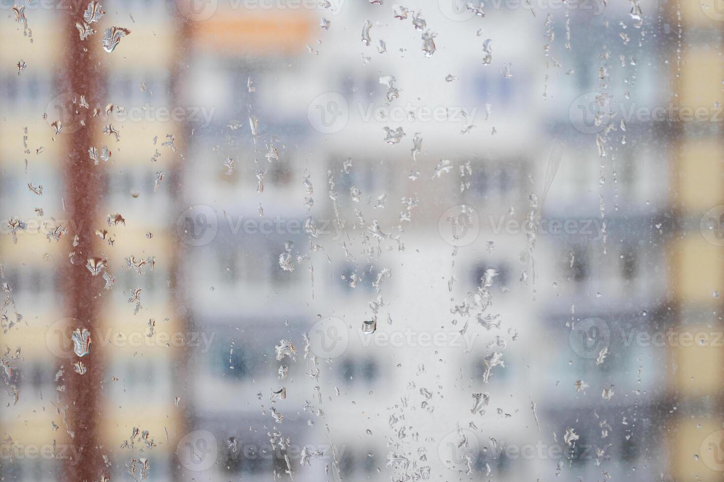 View through a rainy window on a blurred house. Bad rainy weather. photo