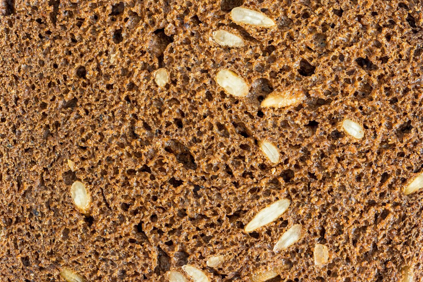 The texture of a slice of black rye bread with seeds. photo