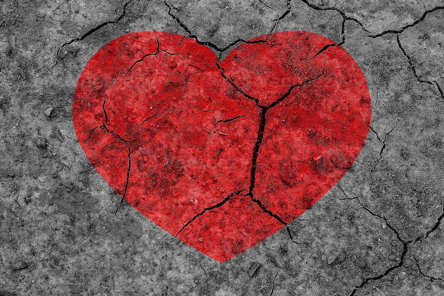 Red heart on a cracked texture. The concept of broken heart and the end of love. photo