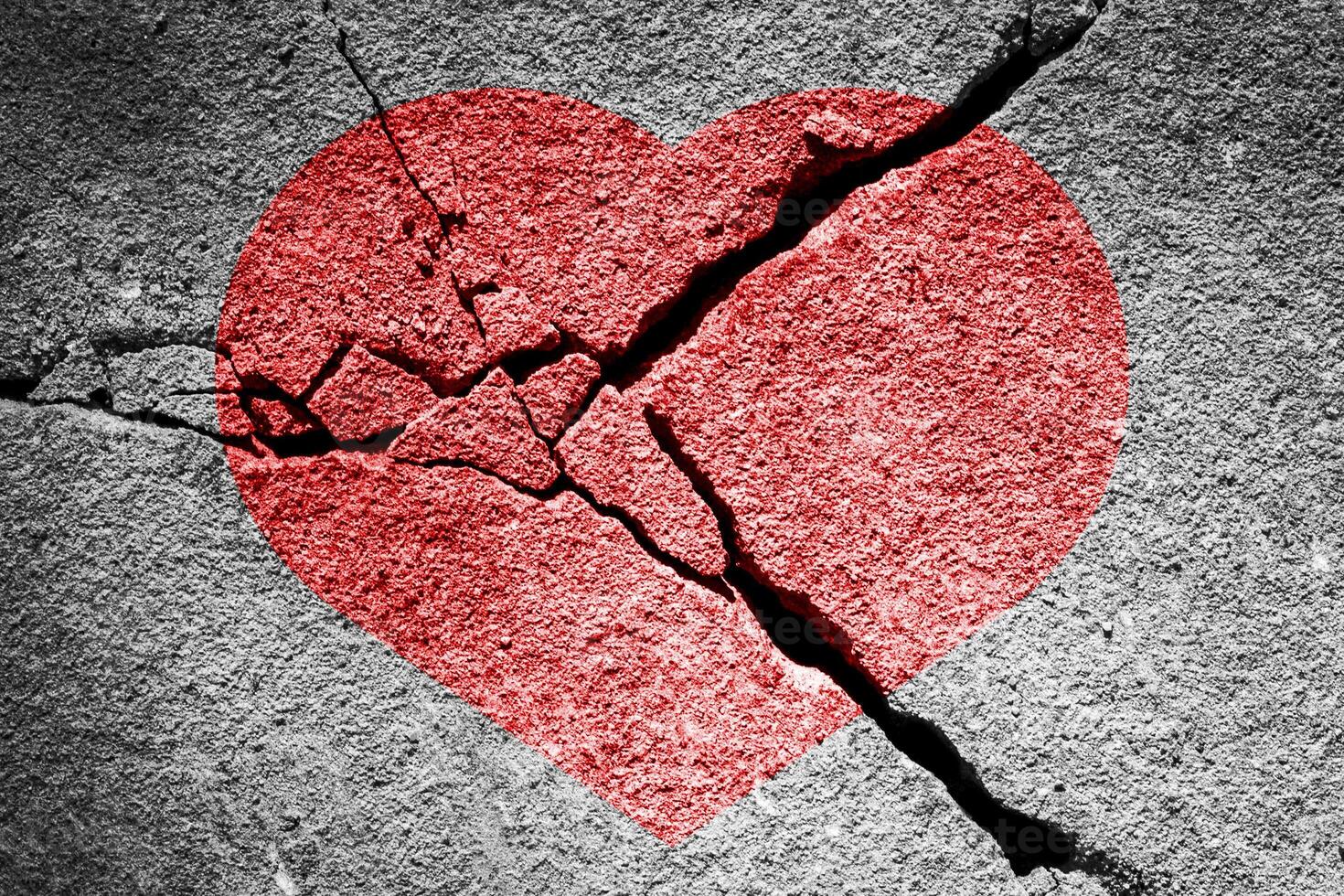 Red heart on a cracked texture. The concept of broken heart and the end of love. photo