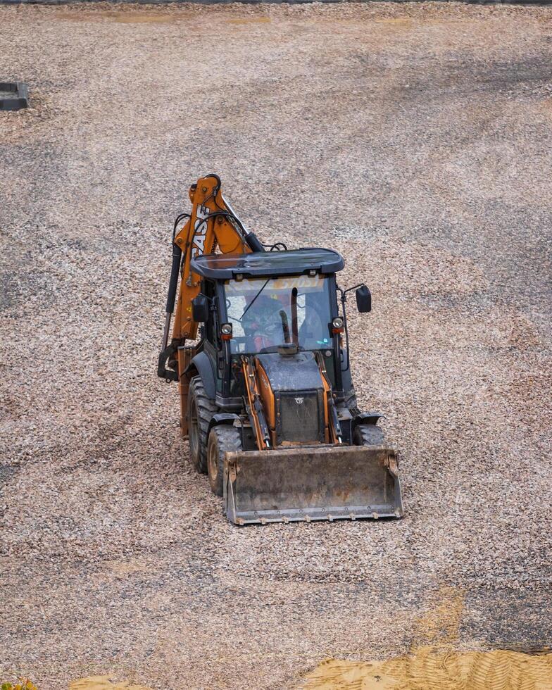 Russia, Kaluga - OCTOBER 27, 2020 Tractor with a bucket leveling gravel for construction. photo