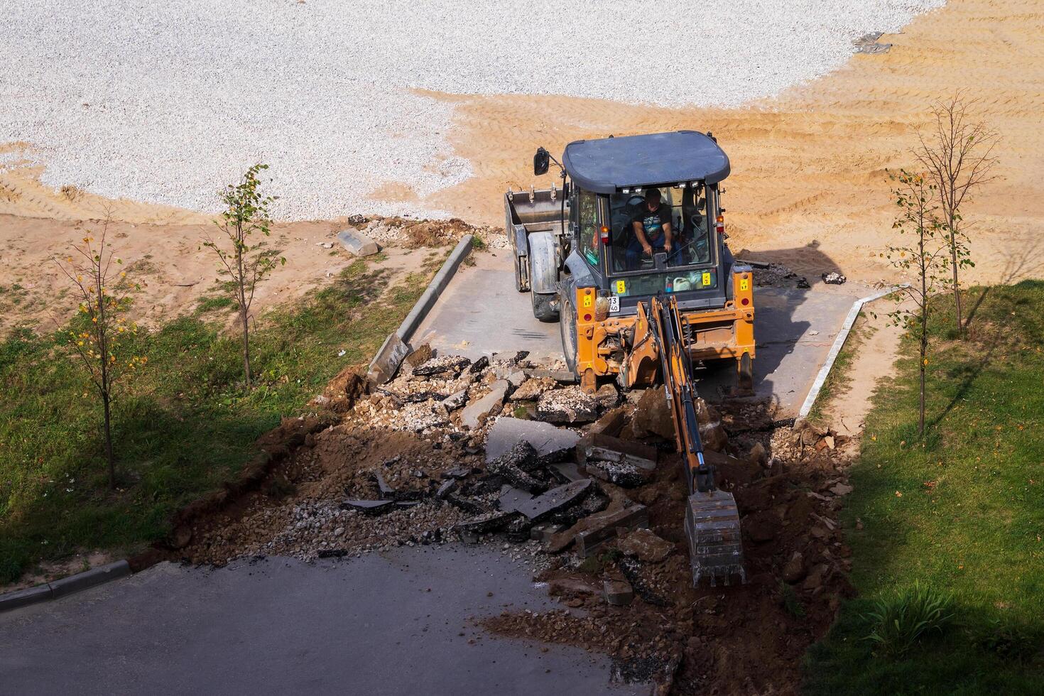 Russia, Kaluga - OCTOBER 27, 2020 Tractor breaking the old asphalt with a bucket before the construction. photo
