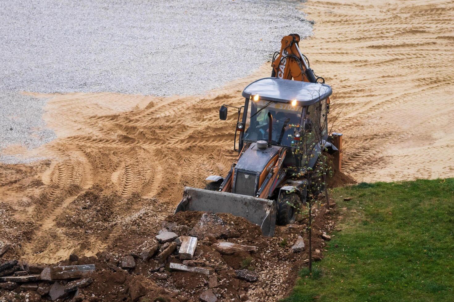 Russia, Kaluga - OCTOBER 27, 2020 Tractor breaking the old asphalt with a bucket before the construction. photo
