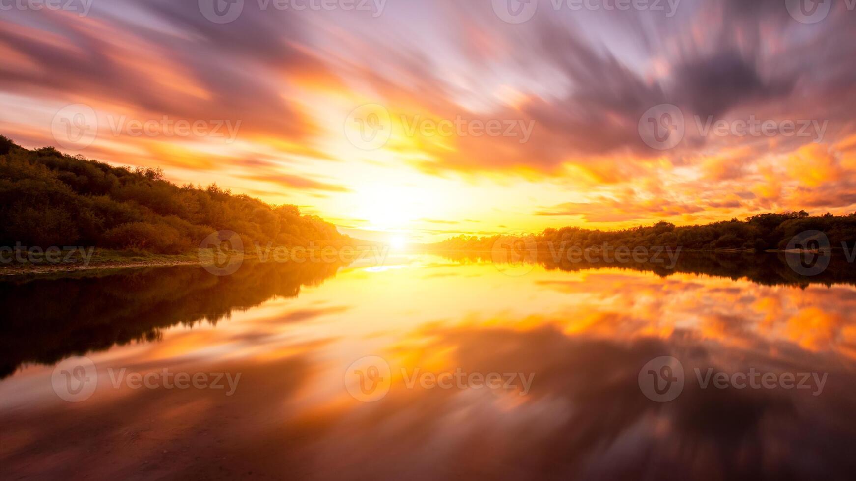 A sunset or sunrise scene over a lake or river with dramatic cloudy skies reflecting in the water on a summer evening or morning. photo