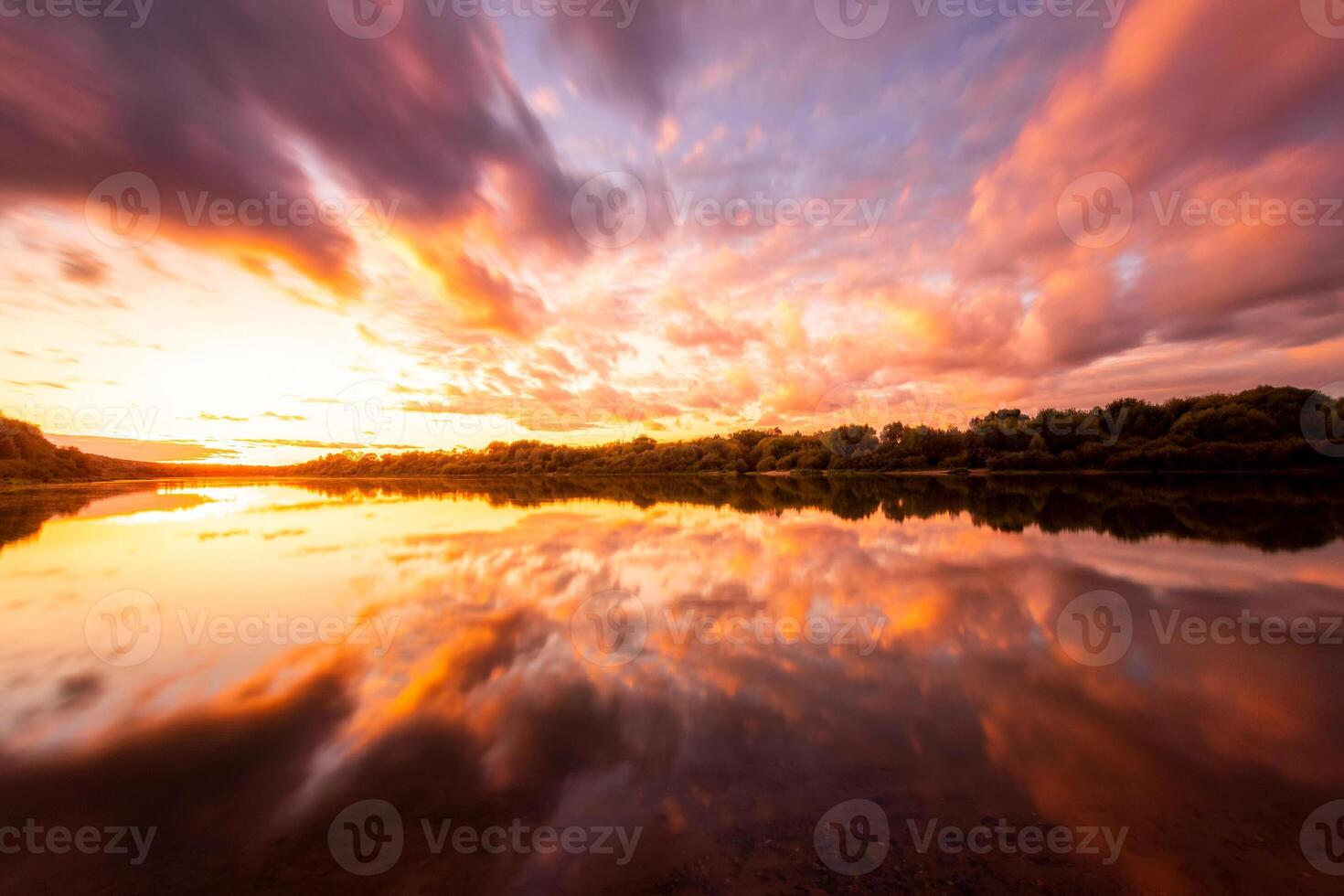 A sunset or sunrise scene over a lake or river with dramatic cloudy skies reflecting in the water on a summer evening or morning. photo