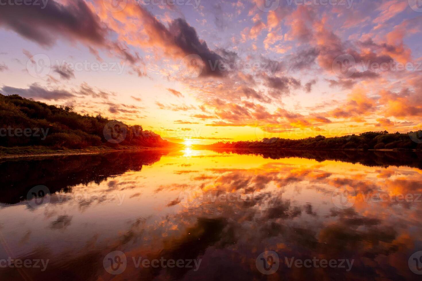 A sunset or sunrise scene over a lake or river with dramatic cloudy skies reflecting in the water on a summer evening or morning. photo