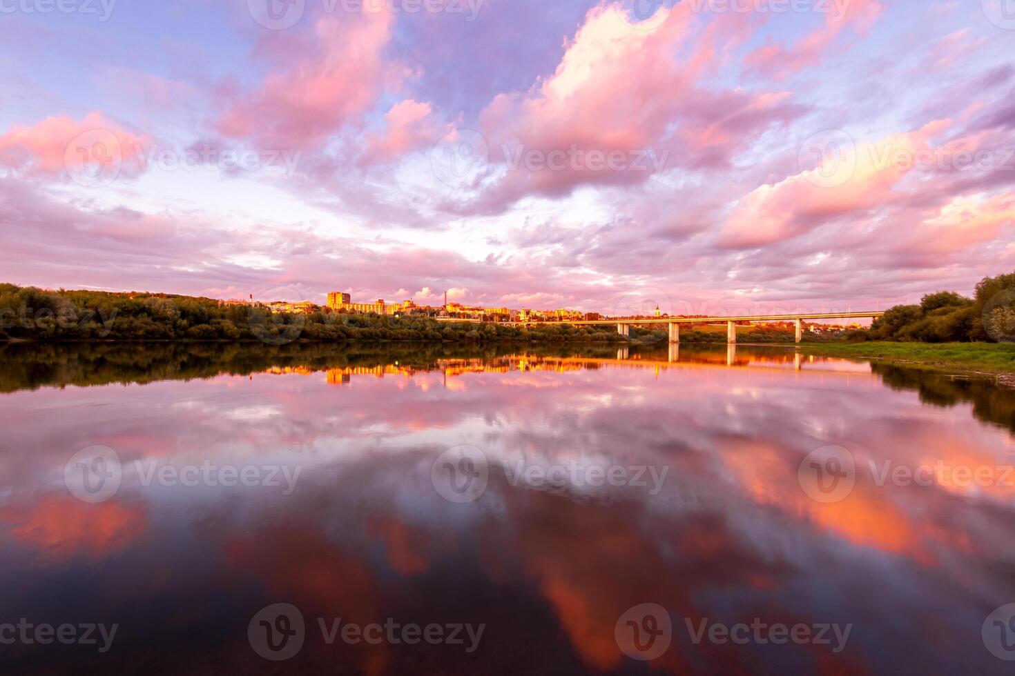 A sunset or sunrise scene over a lake or river with dramatic cloudy skies reflecting in the water on a summer evening or morning. photo