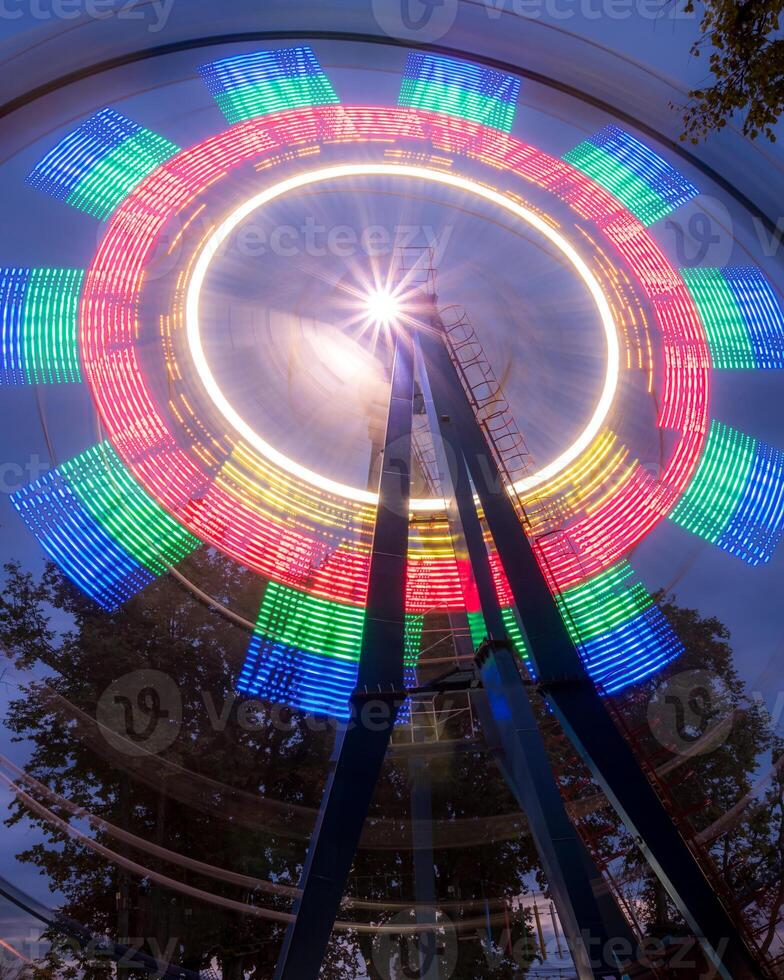 Rotating Ferris wheel in a night park with neon lighting. photo