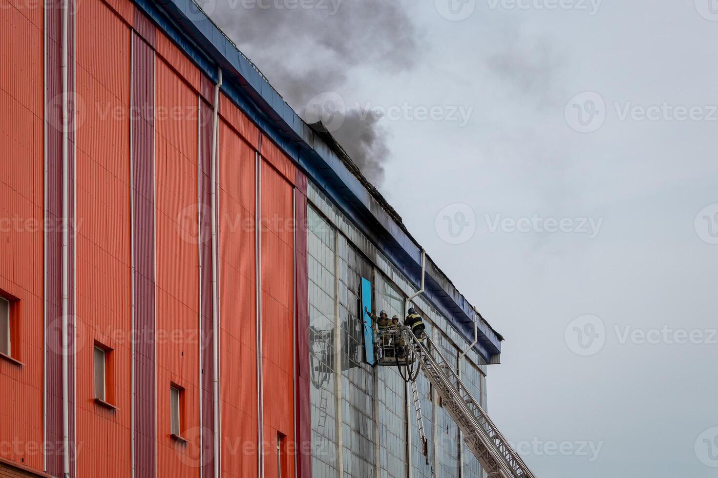 Russia, Kaluga - SEPTEMBER 08, 2020 A team of firefighters in protective suits and helmets on the stairs extinguishing a fire in a building with a broken window. photo