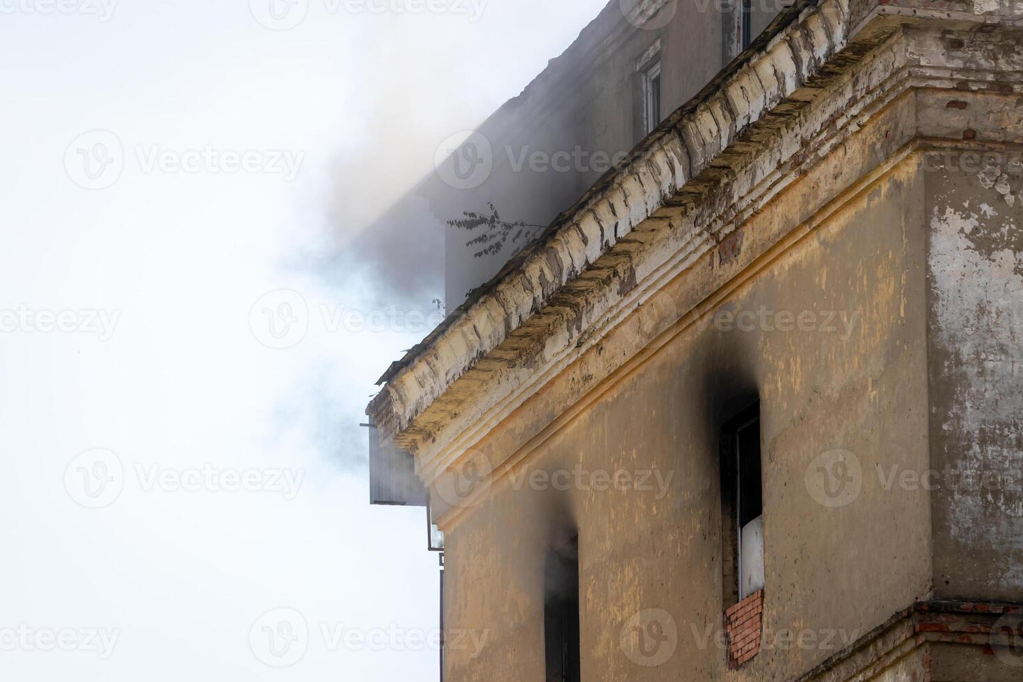 Black smoke rising from a burning building with a cloudy sky. photo