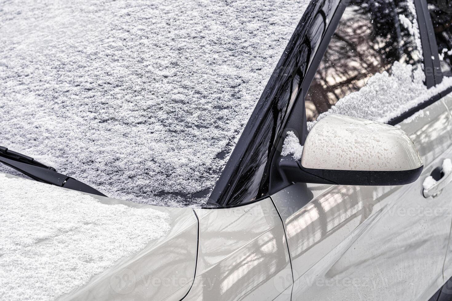 Frozen car windshield covered and rearview mirror with ice and snow on a winter day. photo