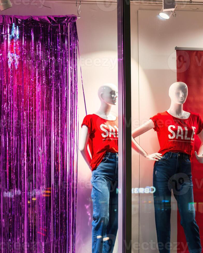 Mannequins in red T-shirts with the inscription SALE on a showcase at night. Friday or celebrating sales concept. photo