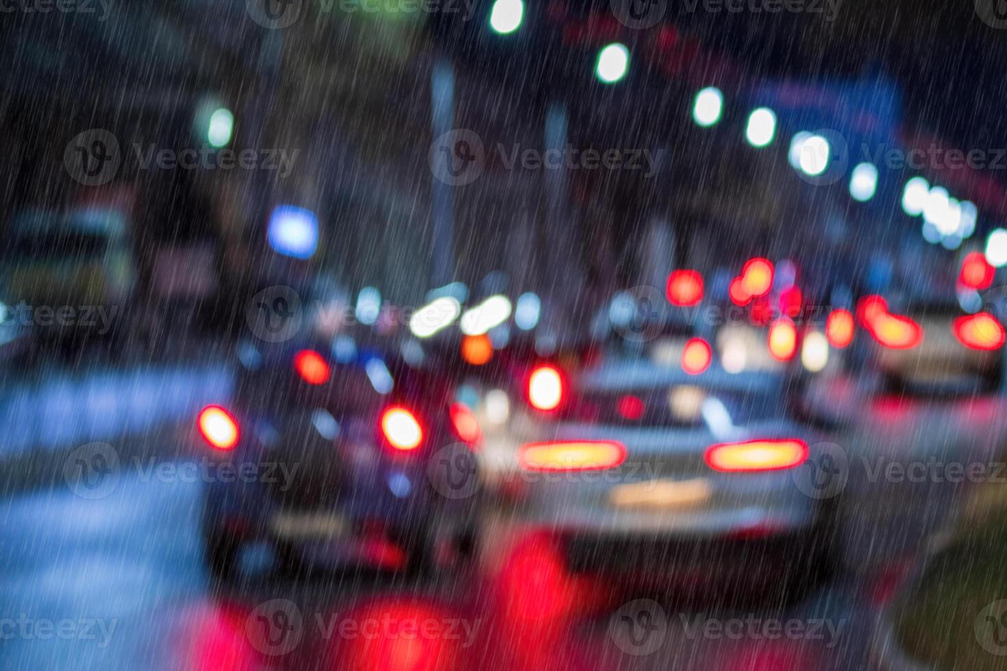 Blurry lights of moving cars and lanterns reflecting on the wet asphalt in the night city in rain. photo
