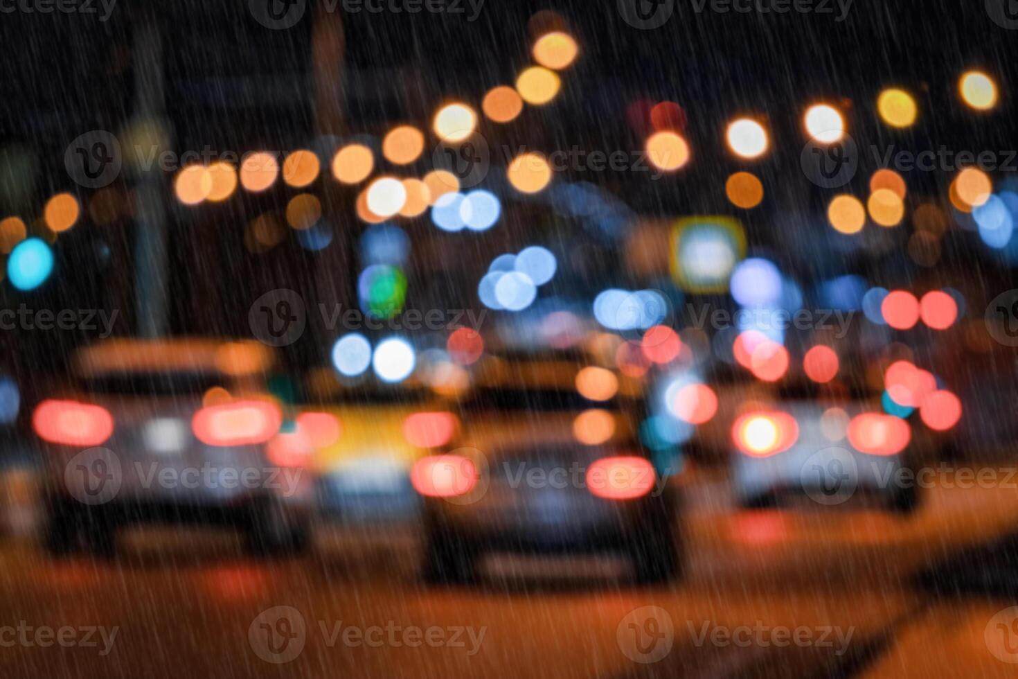 Blurry lights of moving cars and lanterns reflecting on the wet asphalt in the night city in rain. photo