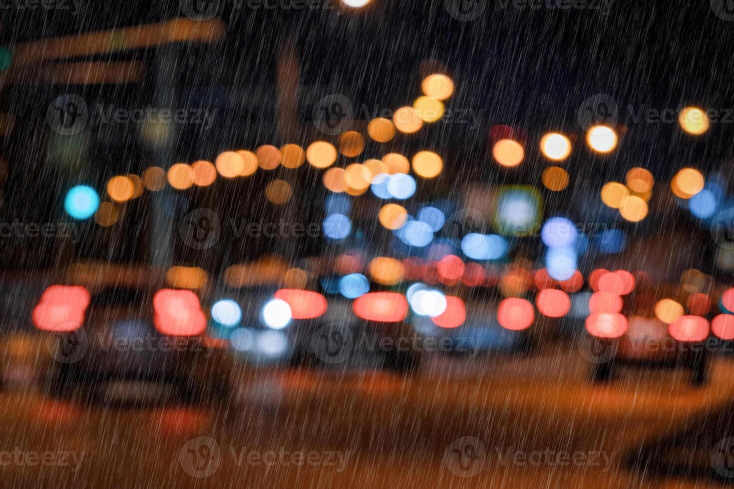 Blurry lights of moving cars and lanterns reflecting on the wet asphalt in the night city in rain. photo