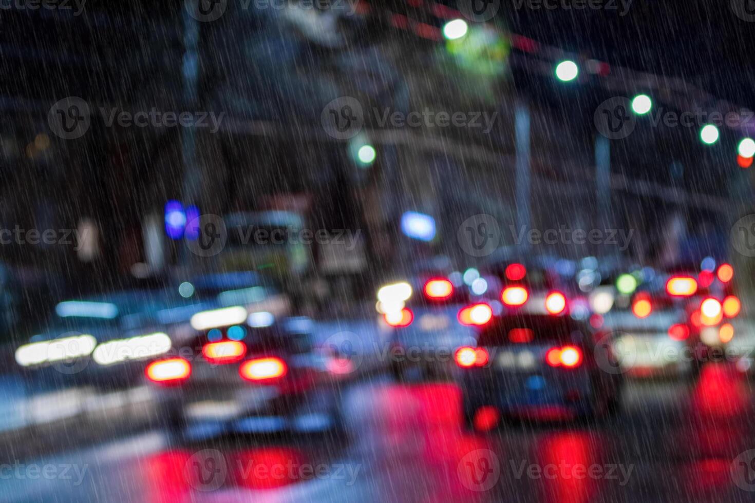 Blurry lights of moving cars and lanterns reflecting on the wet asphalt in the night city in rain. photo