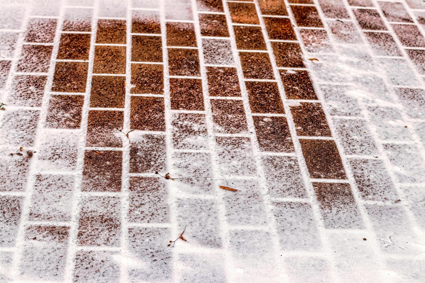 The texture of the cobblestone path covered with the first snow in winter. photo
