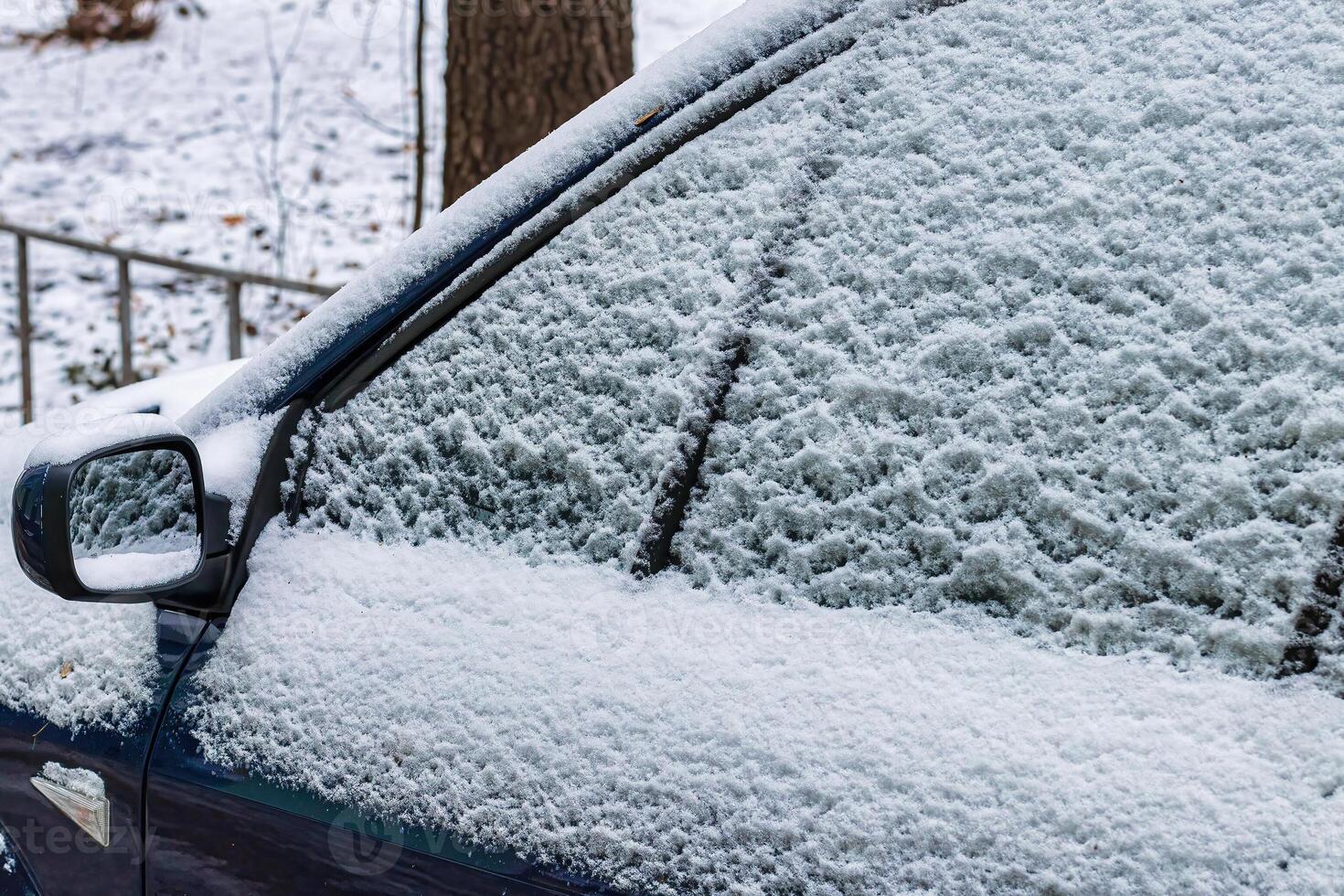 Frozen car windshield covered and rearview mirror with ice and snow on a winter day. photo