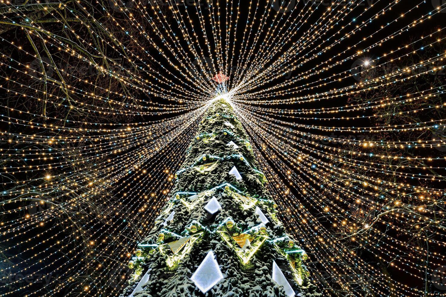 Artificial Christmas tree in garlands at night. photo