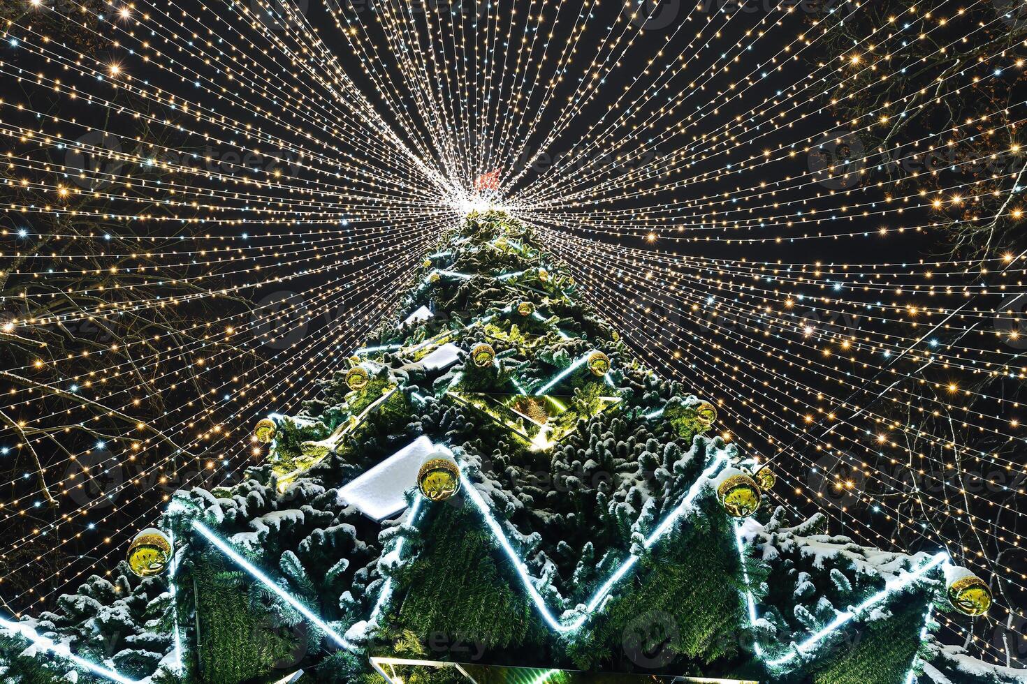 Artificial Christmas tree in garlands at night. photo