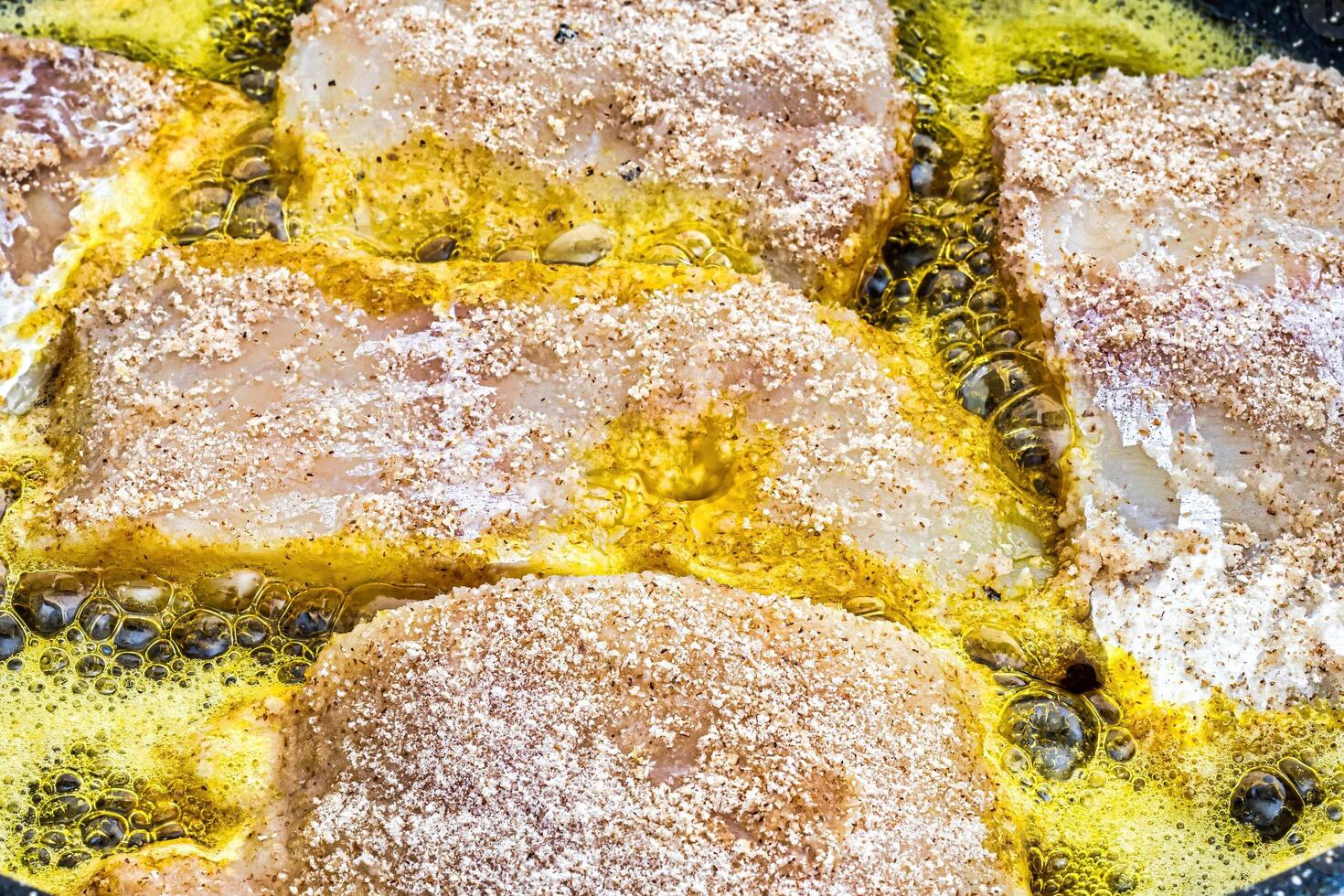 Breaded fish steaks, fried in a pan with vegetable oil. photo