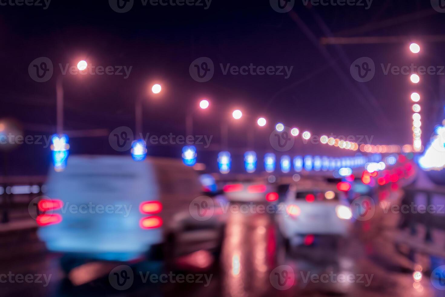 Blurry lights of moving cars and lanterns reflecting on the wet asphalt in the night city. photo