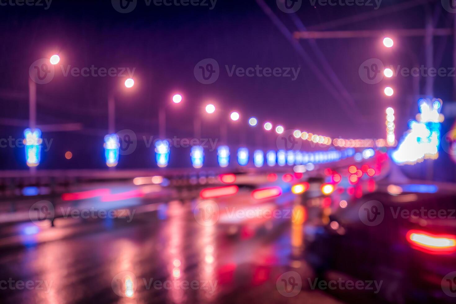 Blurry lights of moving cars and lanterns reflecting on the wet asphalt in the night city. photo