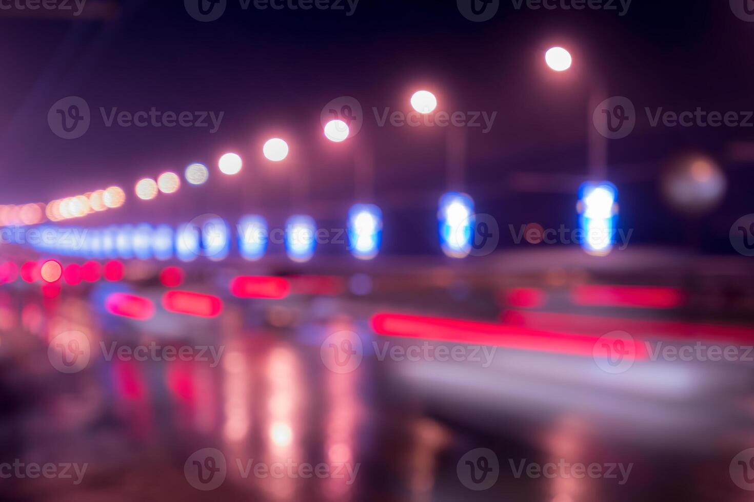 Blurry lights of moving cars and lanterns reflecting on the wet asphalt in the night city. photo