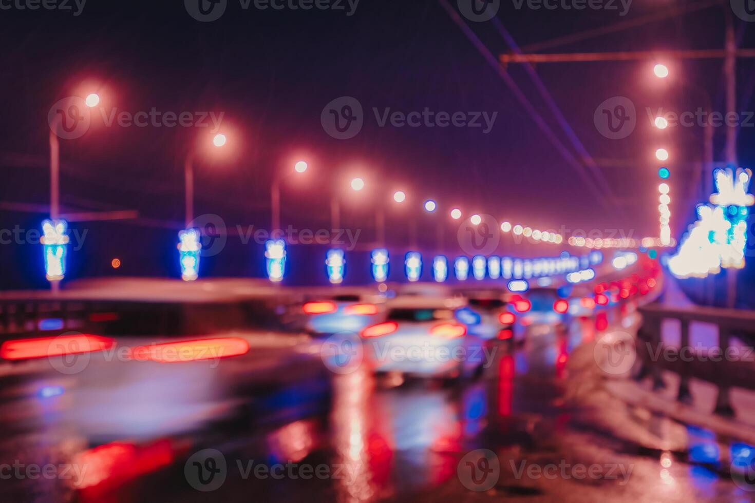 Blurry lights of moving cars and lanterns reflecting on the wet asphalt in the night city. photo