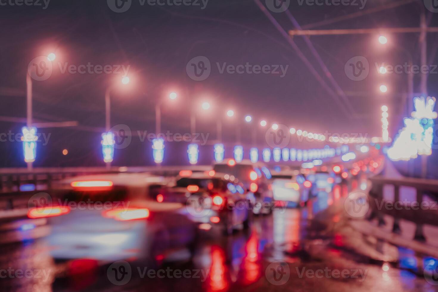 Blurry lights of moving cars and lanterns reflecting on the wet asphalt in the night city. photo