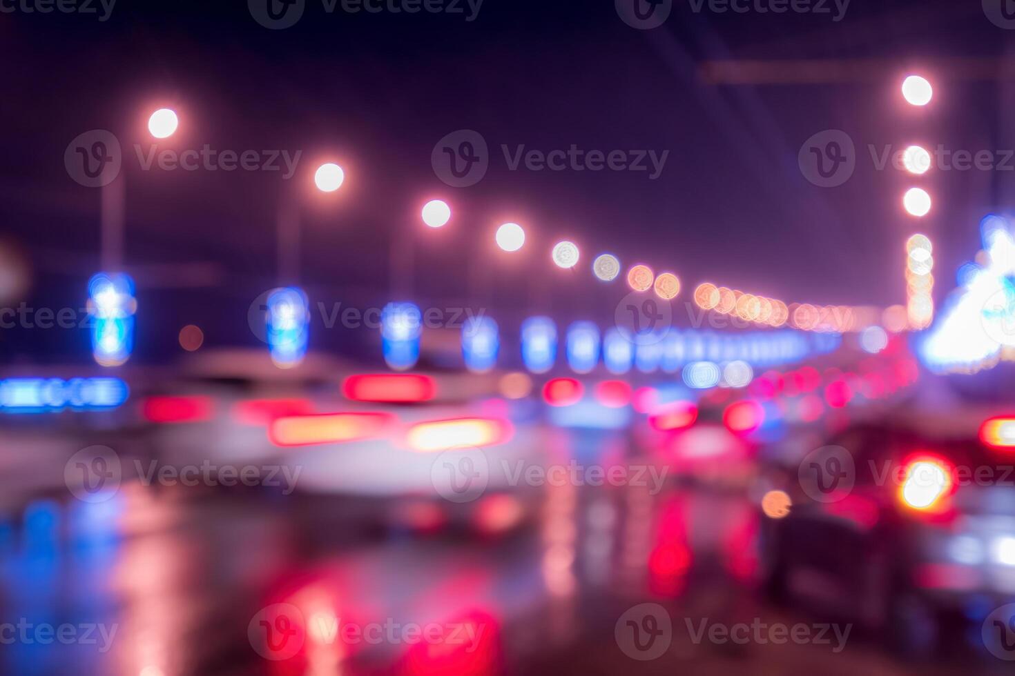 Blurry lights of moving cars and lanterns reflecting on the wet asphalt in the night city. photo